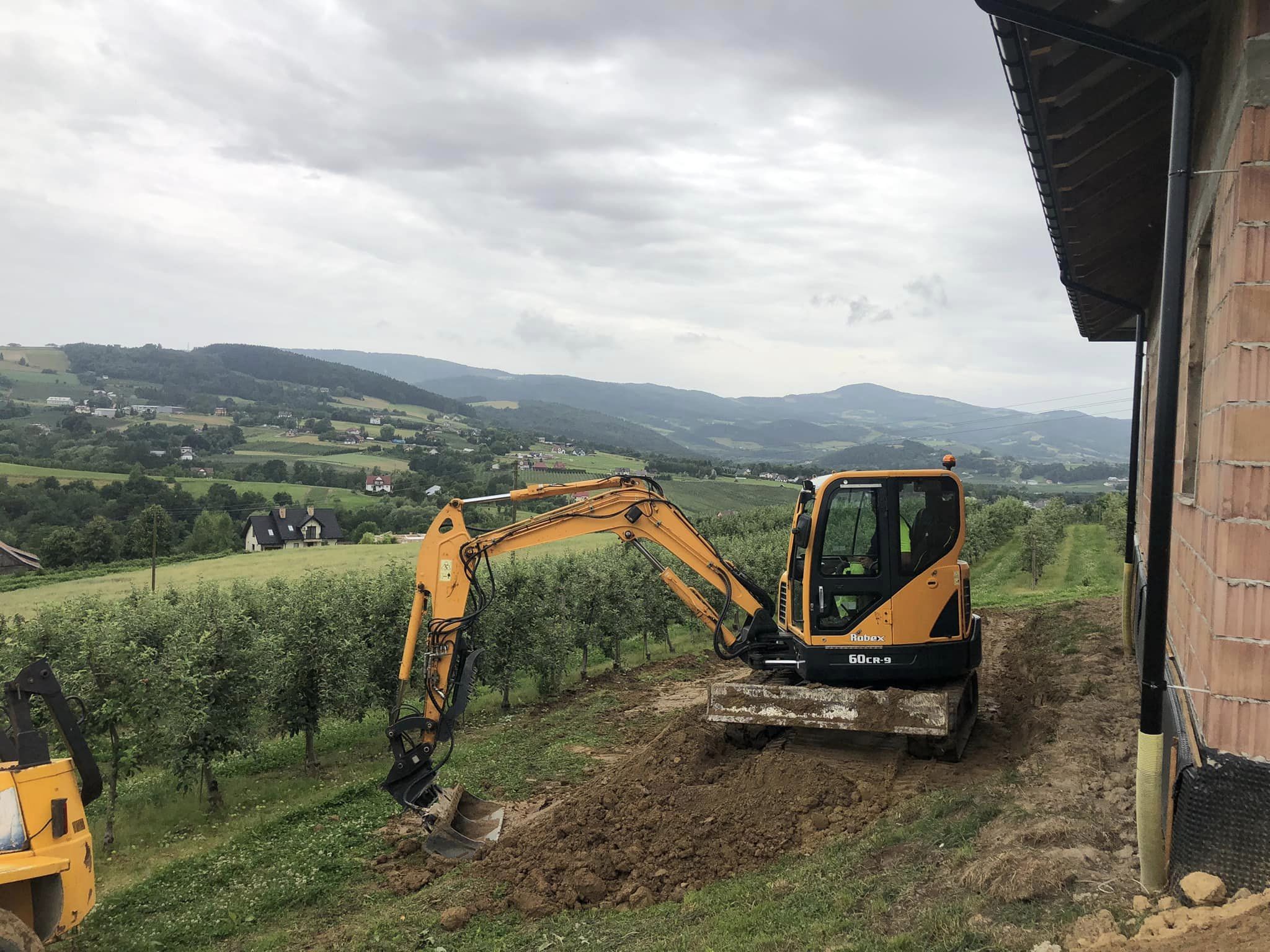 Koparka wykonująca wykop w terenie górzystym
